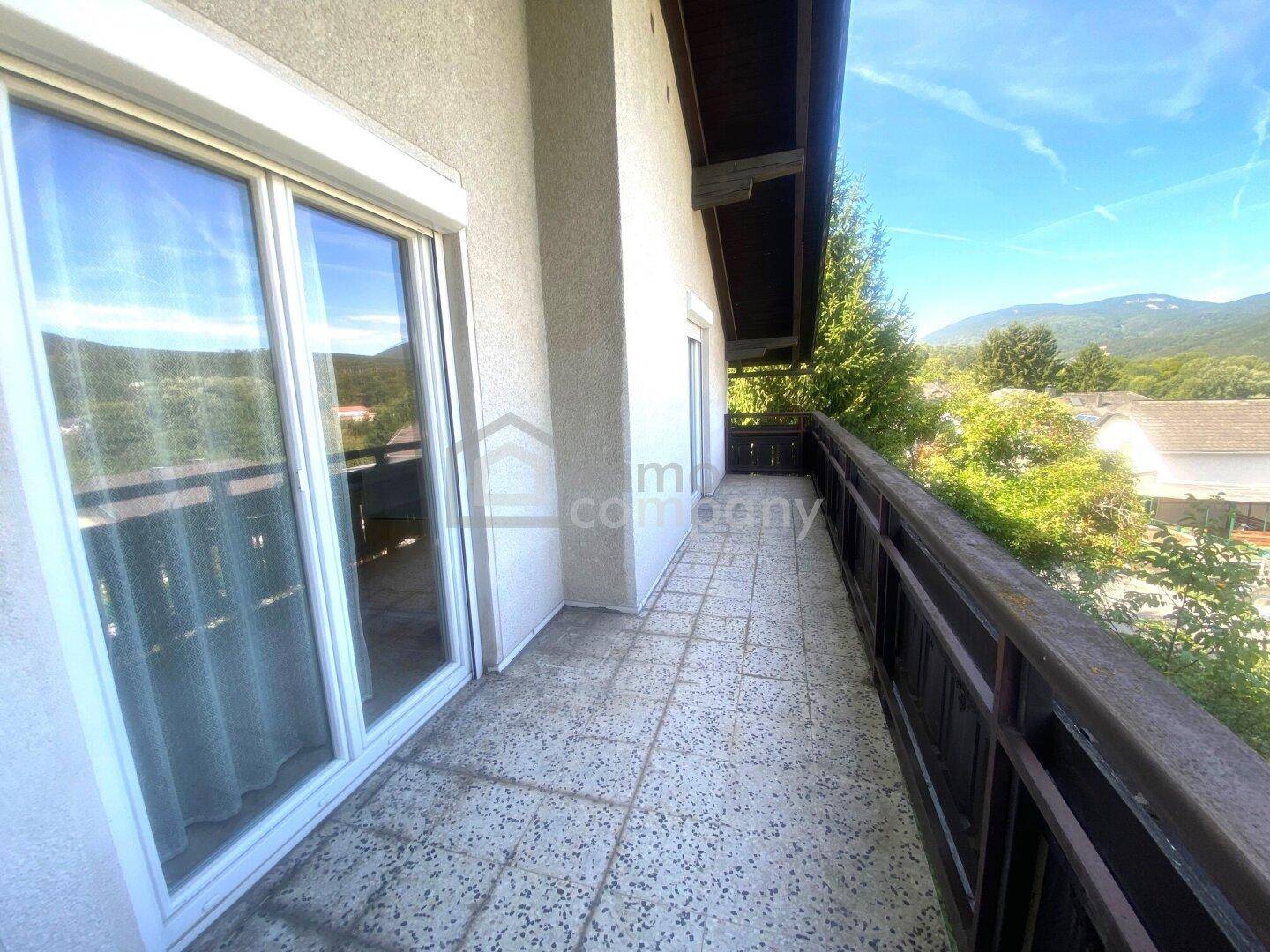 Langer Balkon mit Fliesenboden und weitem Blick auf die umliegende Landschaft.