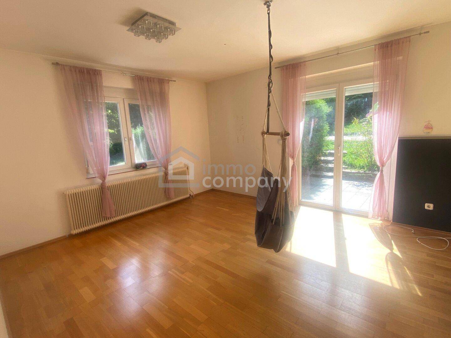 Geräumiges Wohnzimmer mit Holzboden und direktem Zugang zur Terrasse oder Garten.