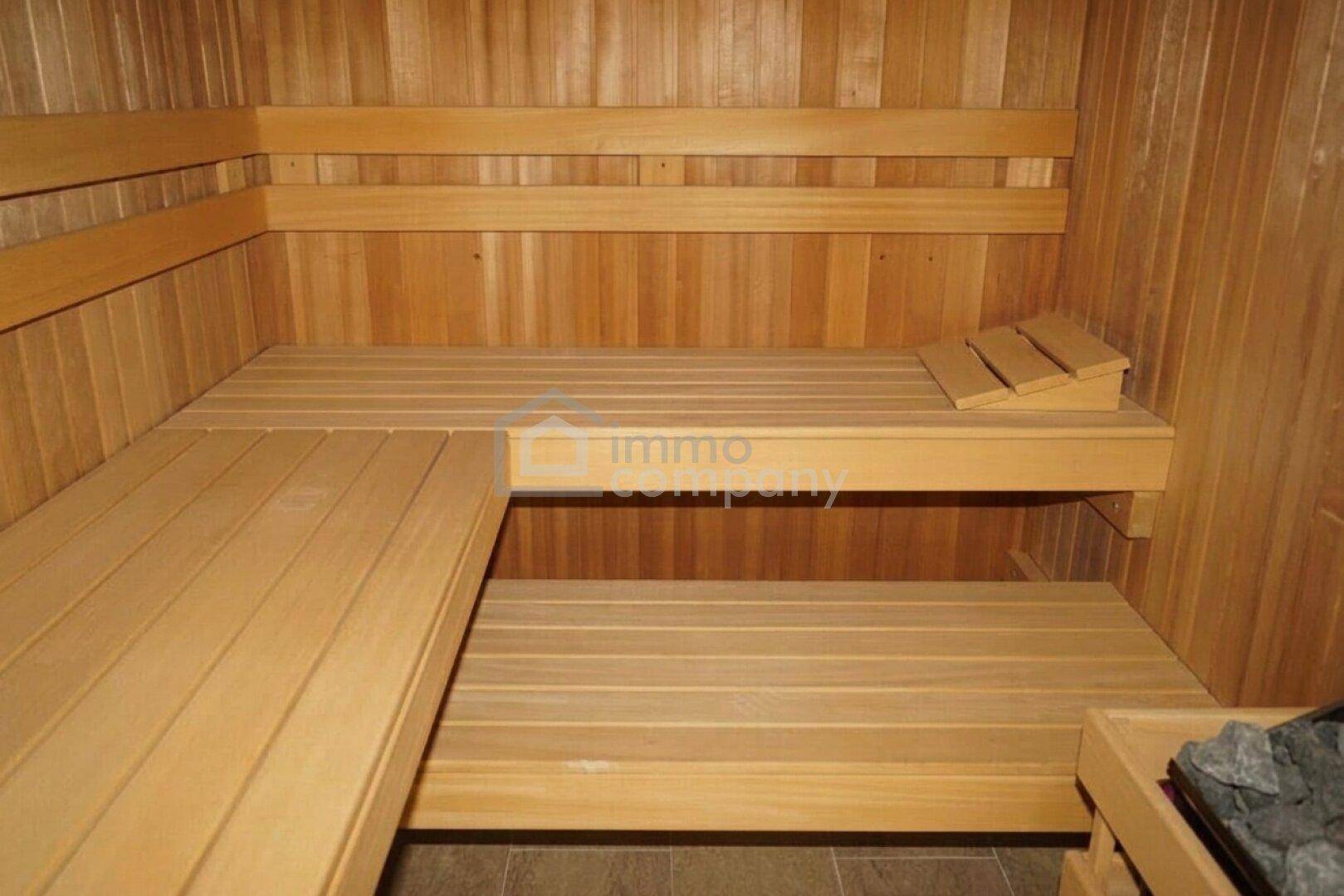 Traditionelle Holzsauna mit mehrstufigen Bänken und einem Saunaofen für Entspannung.