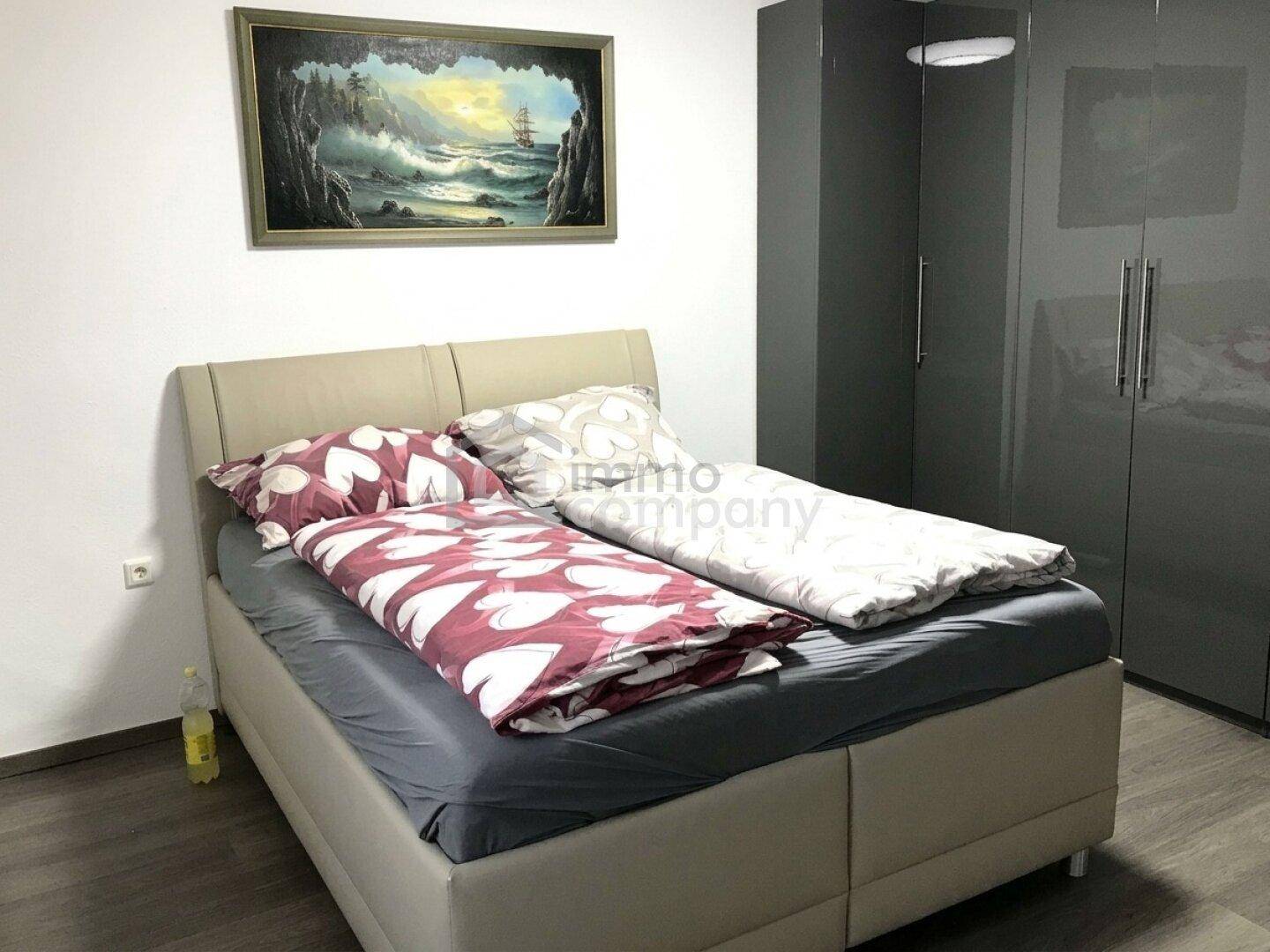 Schlafzimmer mit Doppelbett, modernem Kleiderschrank und Laminatboden.
