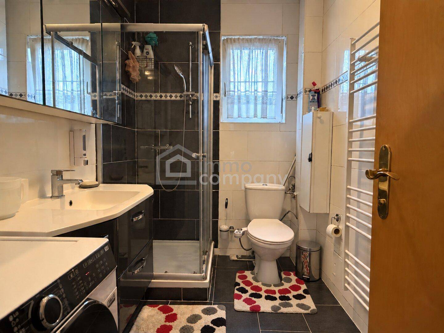 Modernes Badezimmer mit Dusche, Waschbecken, WC und beheiztem Handtuchhalter.