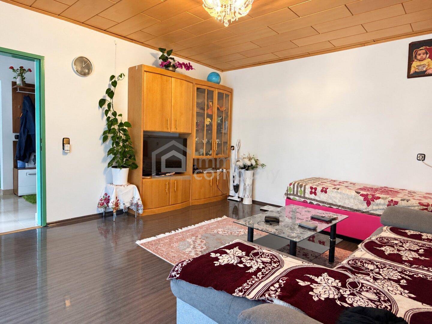 Gemütliches Wohnzimmer mit dunklem Laminatboden, Holzdecke und bequemen Sofas.