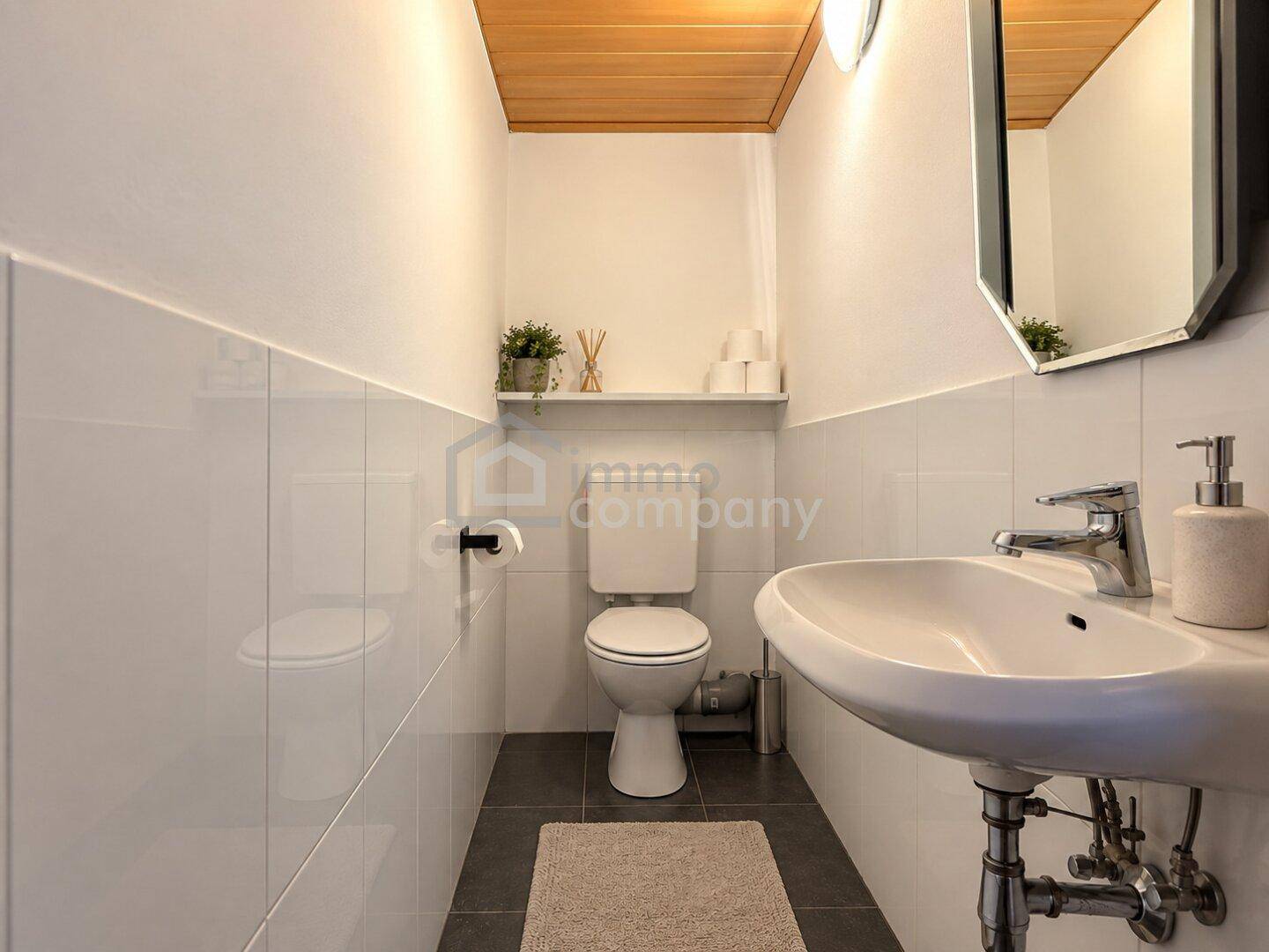Gäste-WC mit modernem Waschbecken, wandhängendem WC und weißen Fliesen.