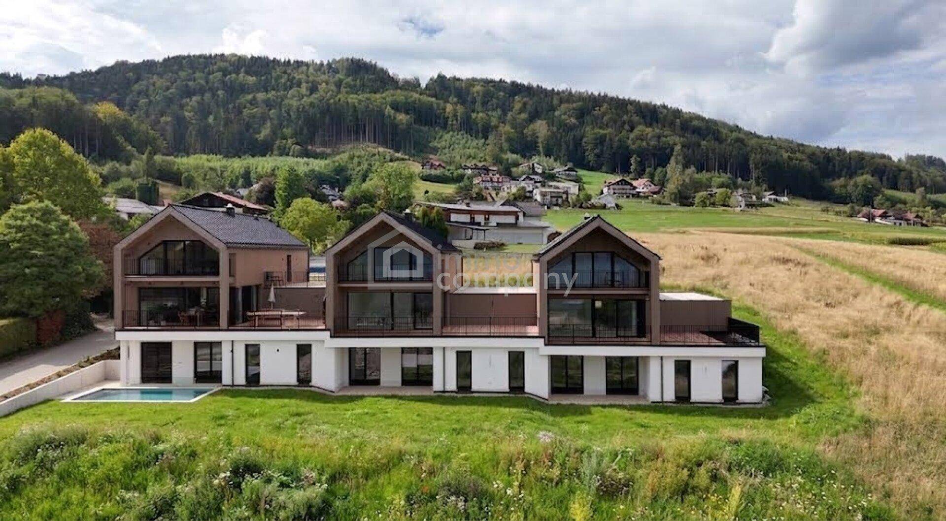 Drei moderne Häuser mit Holzfassade, kleinem Pool und weitem Blick auf die Landschaft.