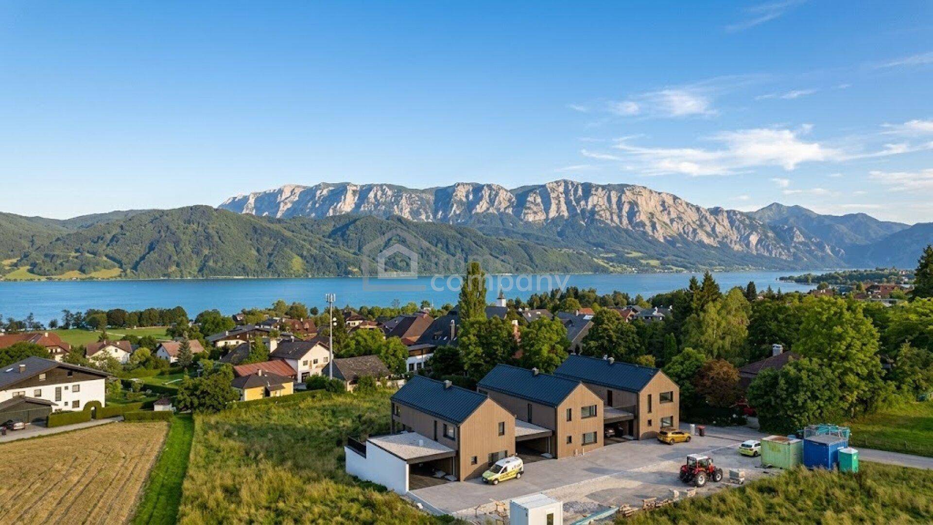 Luftaufnahme der modernen Reihenhäuser mit See- und Bergblick in idyllischer Landschaft.