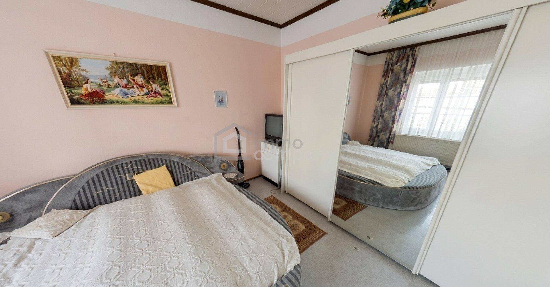 Schlafzimmer mit zwei runden Betten, rosa Wänden und einem großen Spiegelschrank.