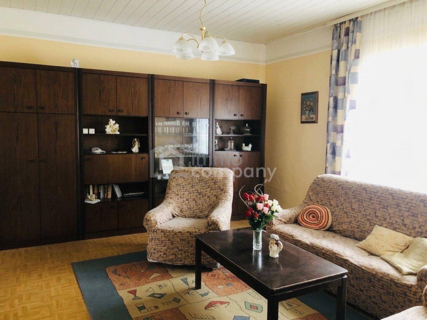 Gemütliches Wohnzimmer mit traditionellen Möbeln, Sofa, Sessel und großem Wandschrank.