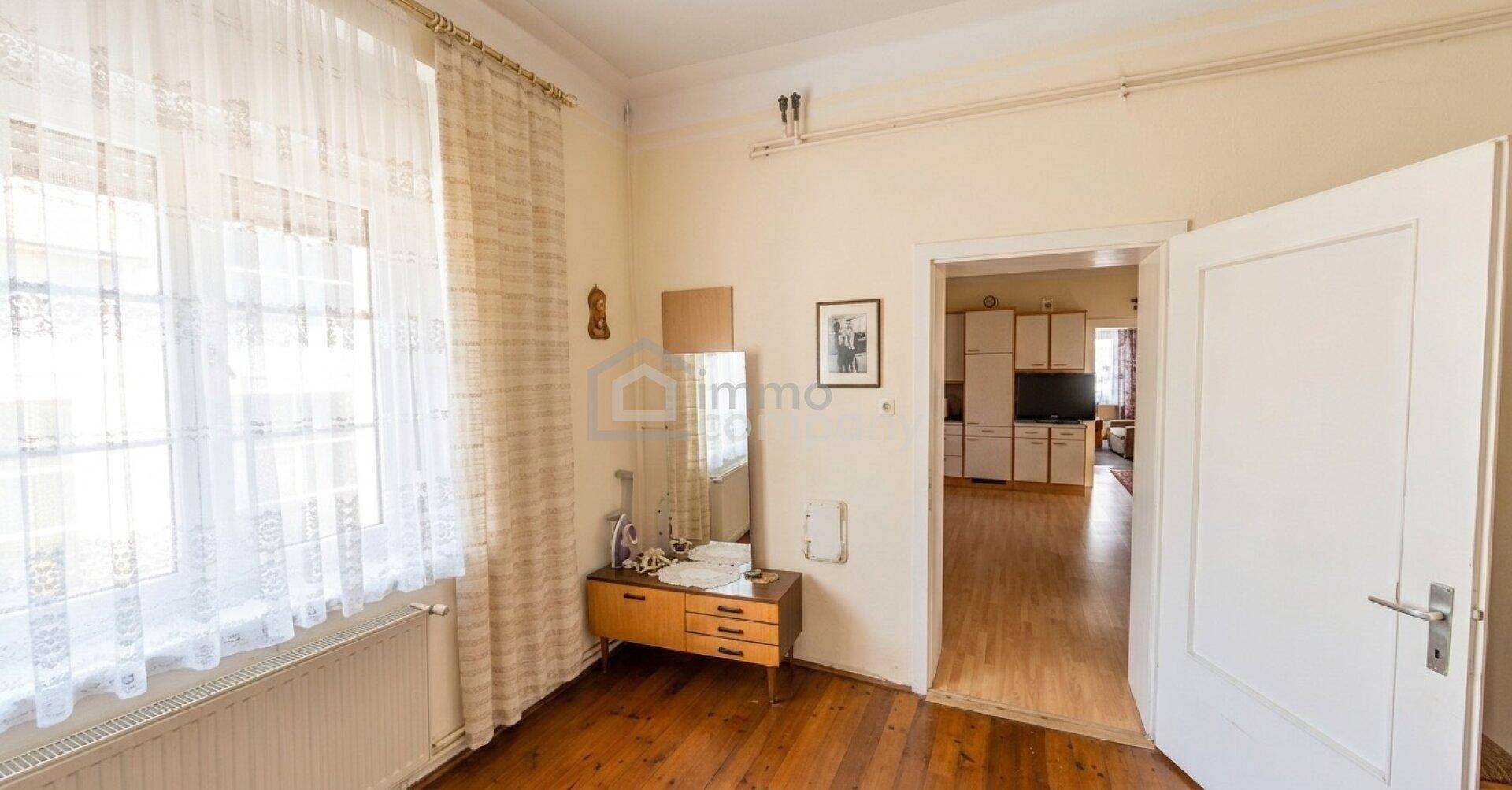 Heller Raum mit großem Fenster, einem Spiegel und Zugang zur Küche.