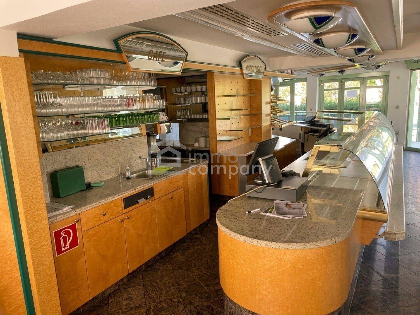 Thekenbereich eines Cafés mit Vitrinen, Spülbecken und Regalen voller Gläser, bereit für den Service.
