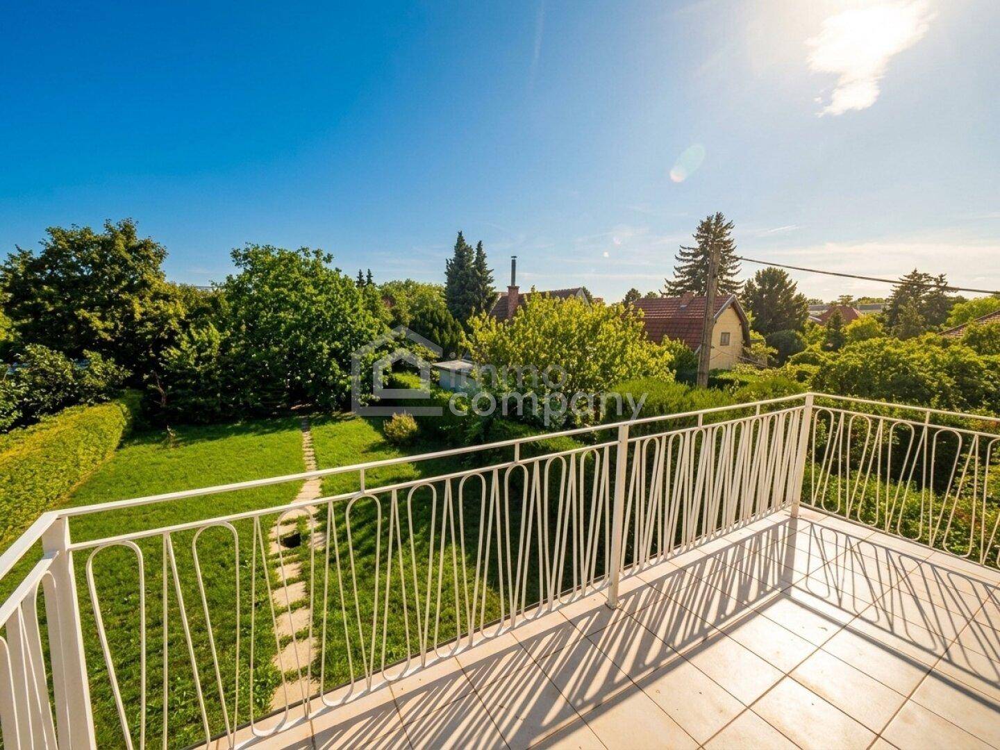 Heller Balkon mit weitem Blick über den Garten und die sonnige Umgebung.