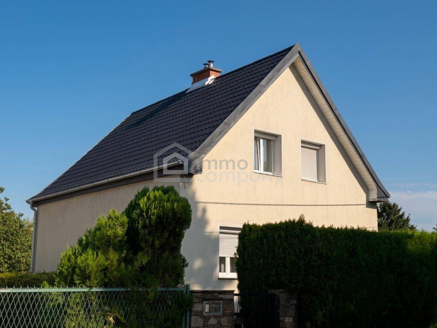 Seitenansicht des Einfamilienhauses mit Satteldach und gepflegter Hecke im Vordergrund.