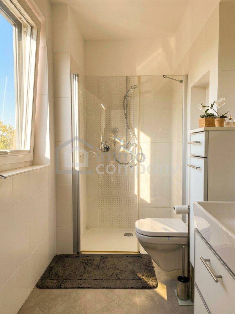 Helles Badezimmer mit Duschkabine, WC, Einzelwaschbecken und weißen Fliesen.