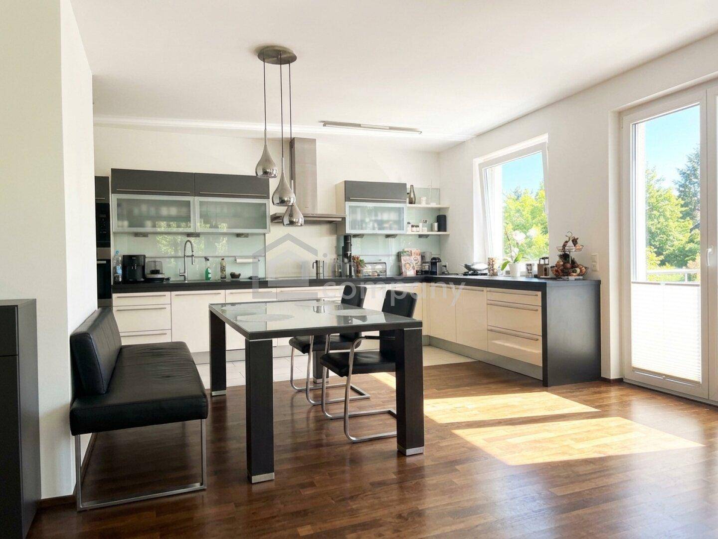Moderne Küche mit Essbereich, Holzboden und Zugang zu einem Balkon oder Terrasse.