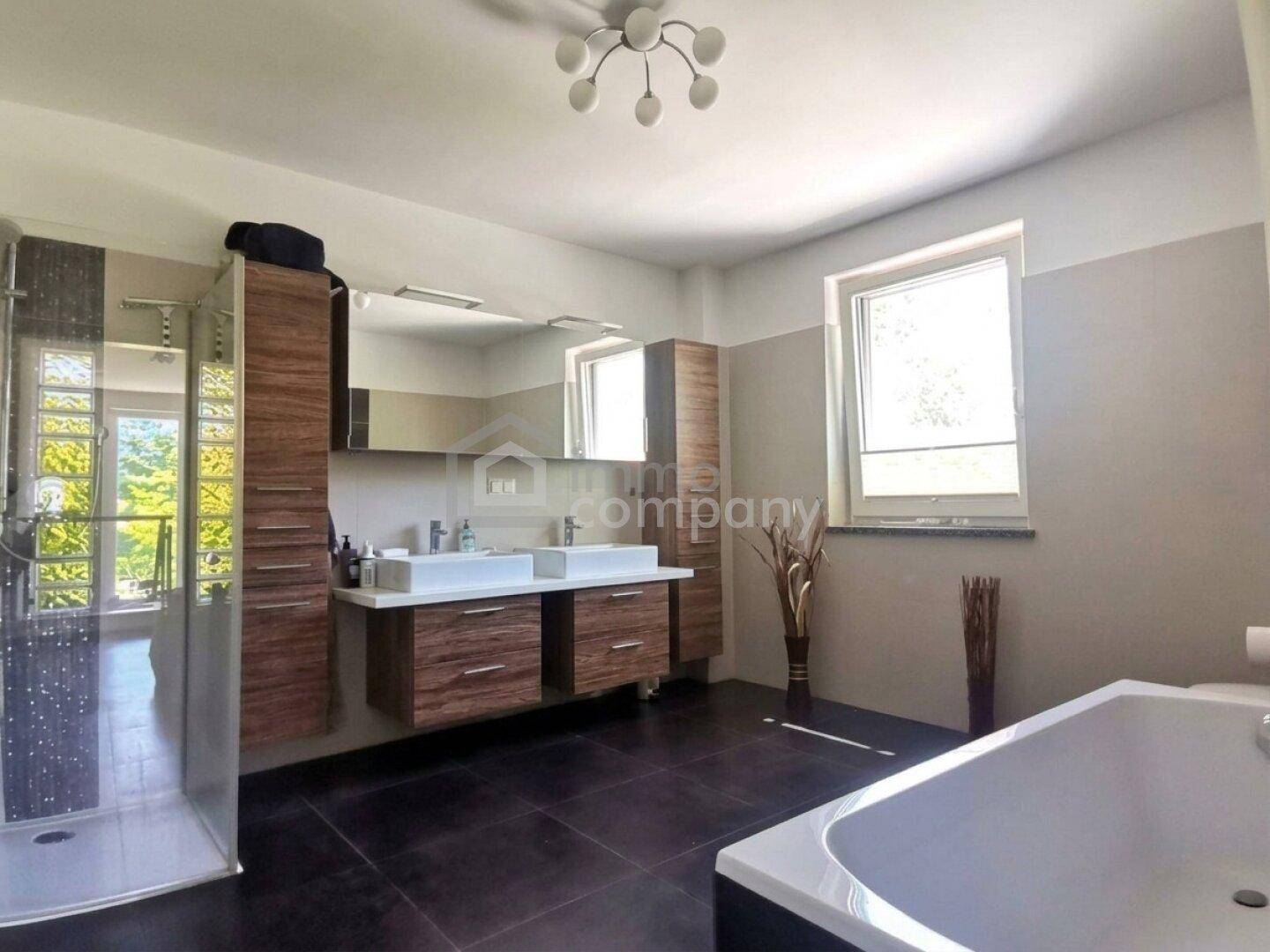 Geräumiges Badezimmer mit Doppelwaschbecken, Badewanne und großer begehbarer Dusche.