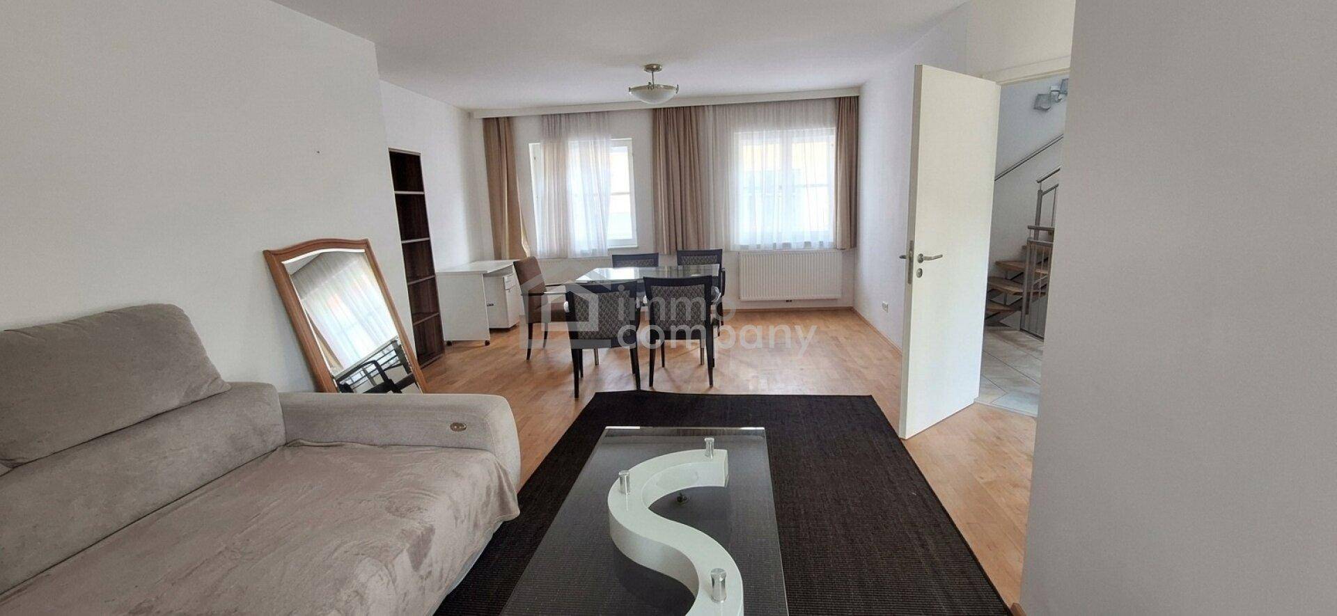 Geräumiger Wohn-Essbereich mit Sofa, Couchtisch und Esstisch, ausgestattet mit Holzfußboden.
