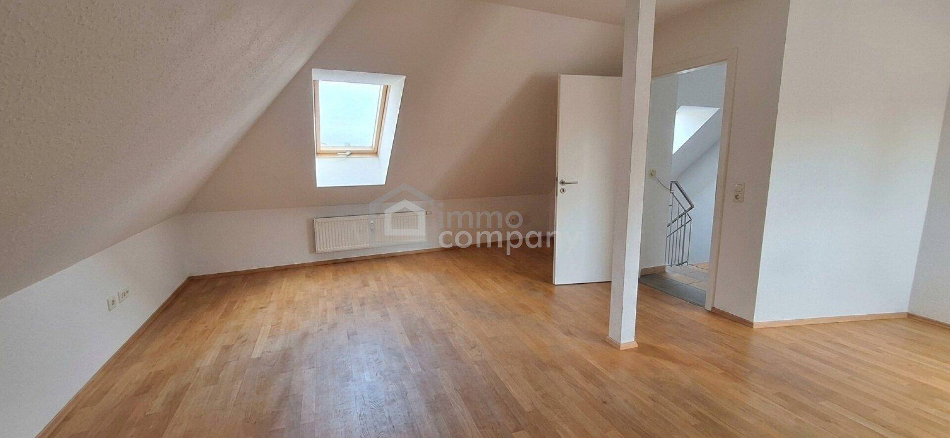 Geräumiges Zimmer im Dachgeschoss mit Holzfußboden, Dachfenster und Zugang zum Treppenhaus.