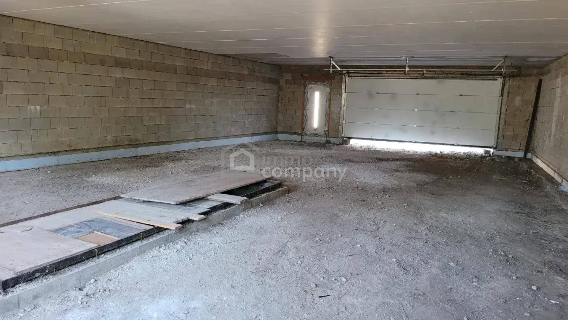 Große, unfertige Garage mit Betonsteinwänden und einer Wartungsgrube für Fahrzeuge.