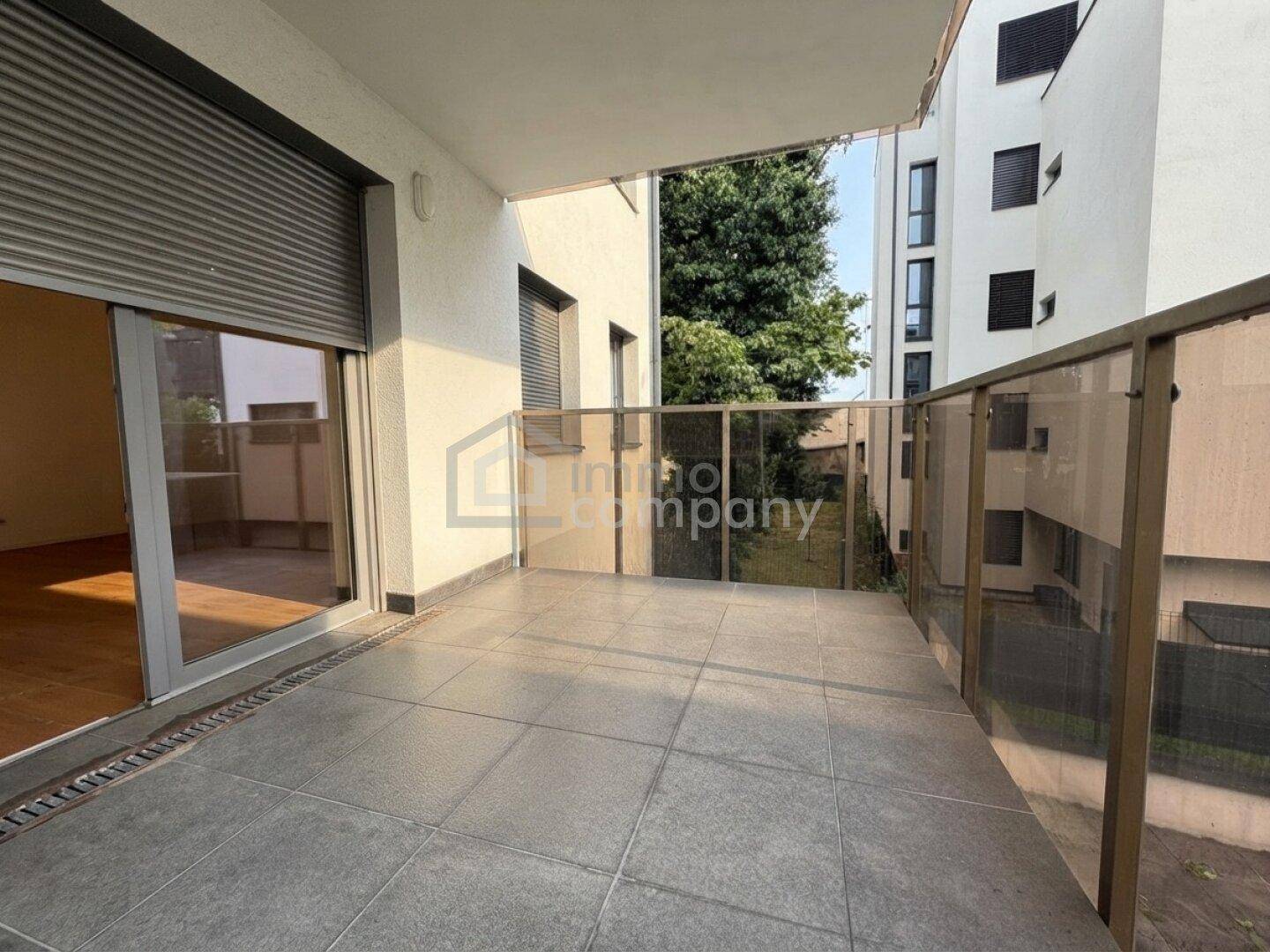 Geräumiger Balkon mit Fliesenboden und Glasgeländer, ideal für entspannte Stunden im Freien.