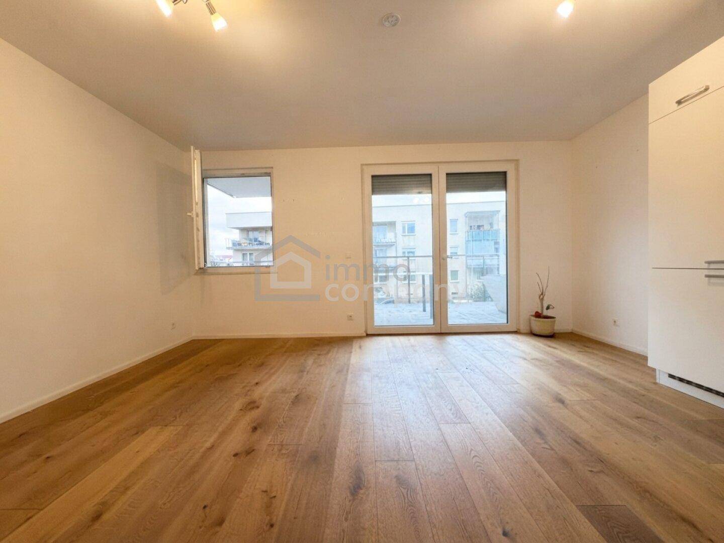 Geräumiges Wohnzimmer mit Holzboden und Zugang zu einem Außenbereich, ideal für helle Einrichtung.
