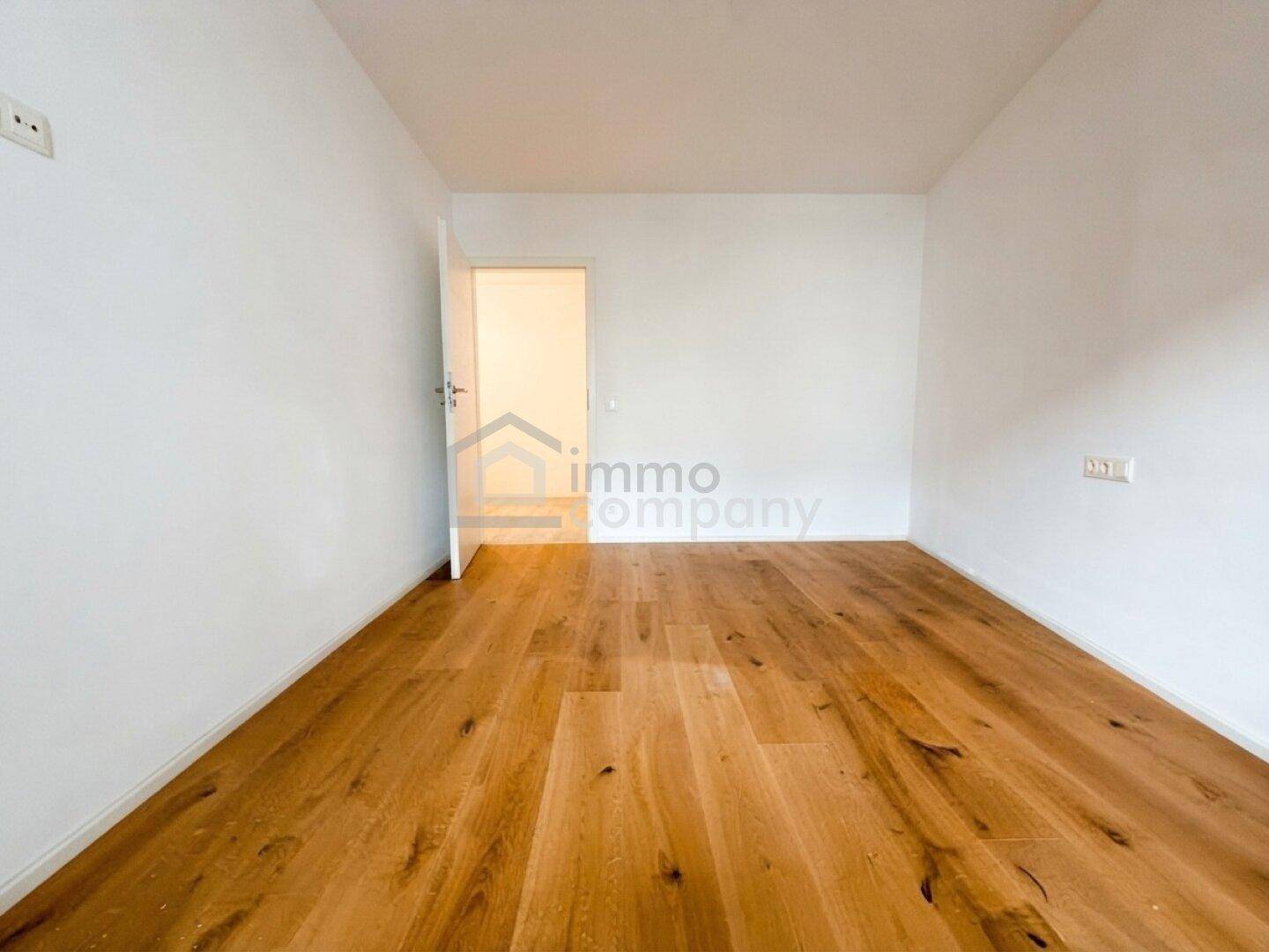 Leeres Schlafzimmer mit Holzboden und hellen Wänden, bereit für individuelle Gestaltung.