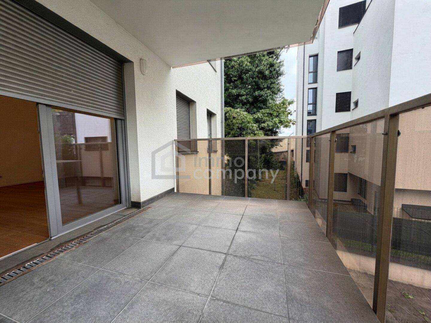 Geräumiger Balkon mit Fliesenboden und Glasgeländer, ideal für Entspannung im Freien.