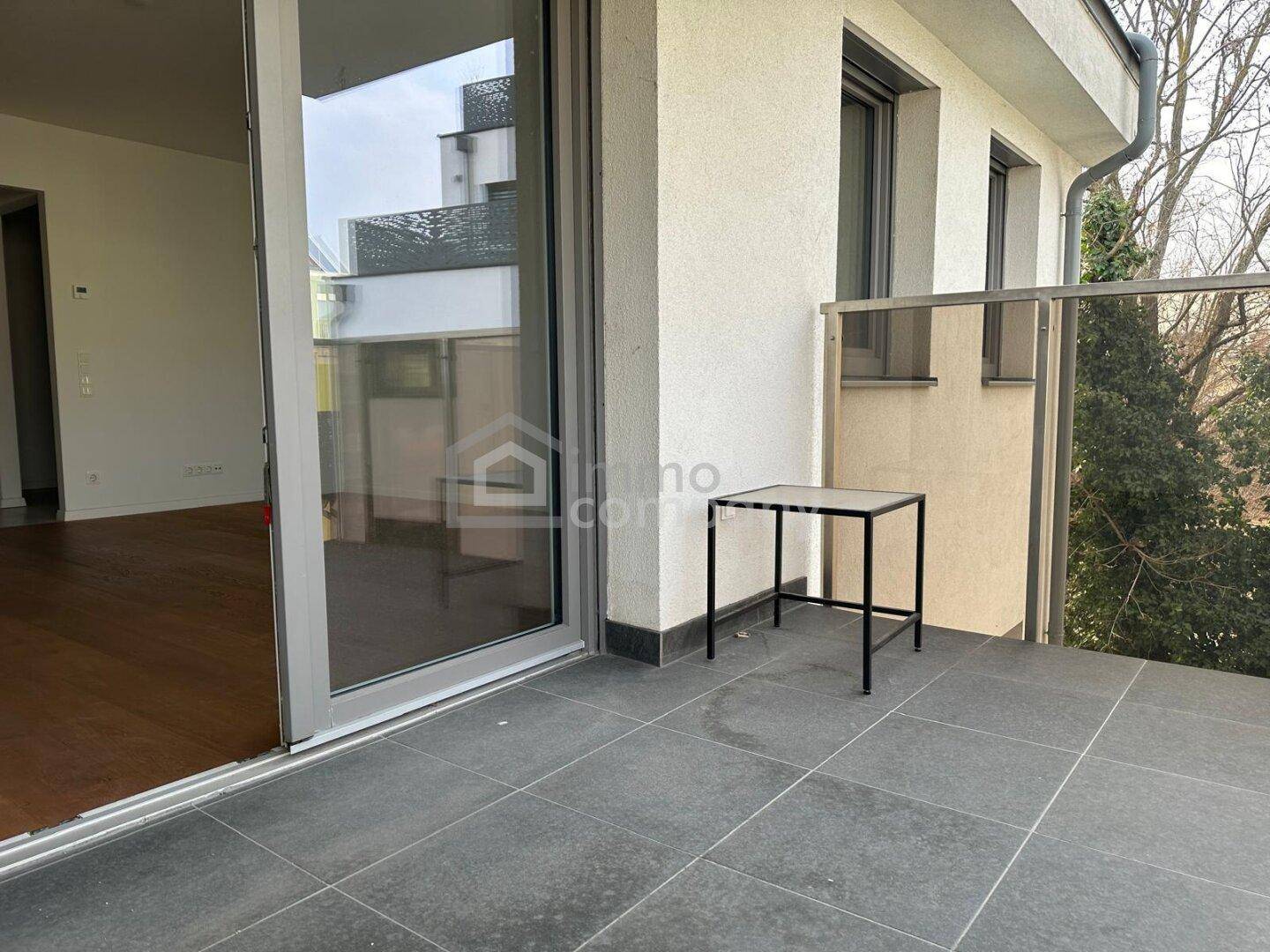 Geräumiger Balkon mit Fliesenboden und Glasgeländer, bereit zur individuellen Gestaltung.