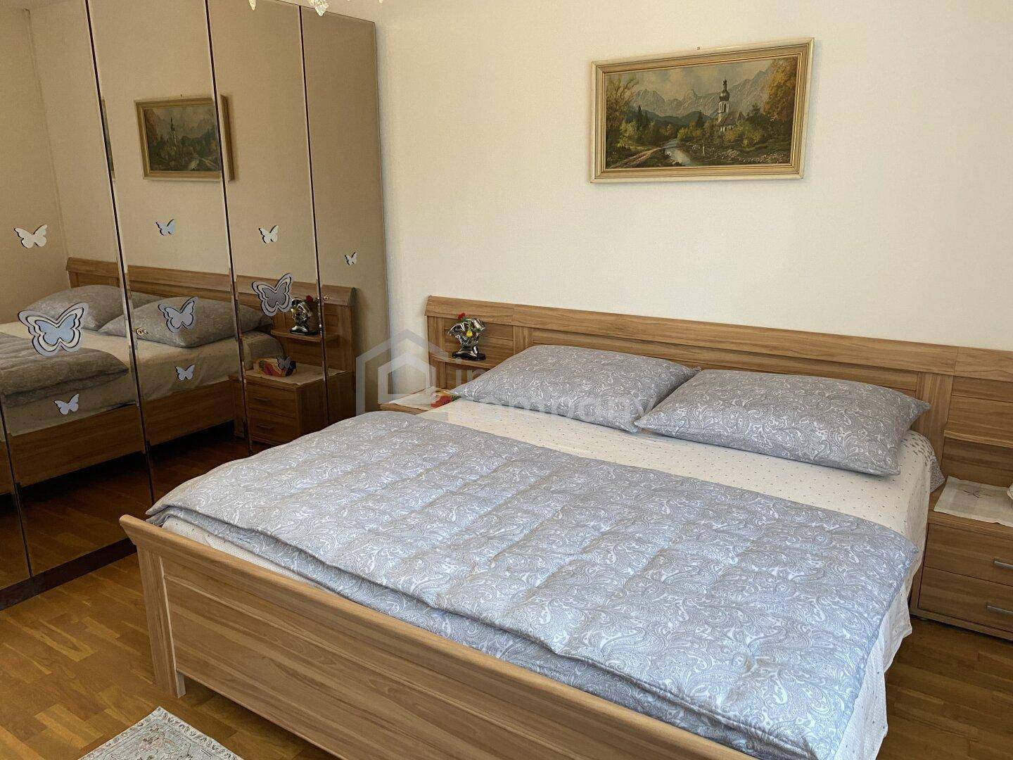 Gemütliches Schlafzimmer mit Doppelbett, Nachttischen und einem großen Spiegelschrank.