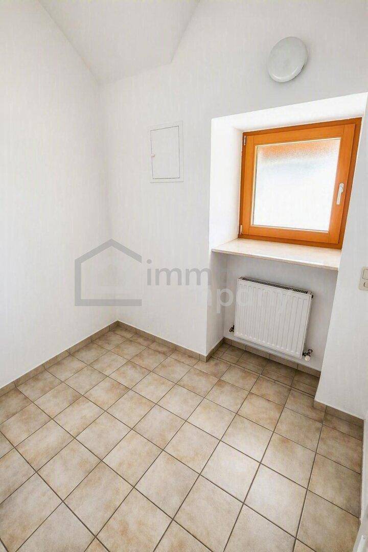Kleiner Raum mit Fliesenboden, Fenster und Heizkörper, geeignet als Abstell- oder Hauswirtschaftsraum.