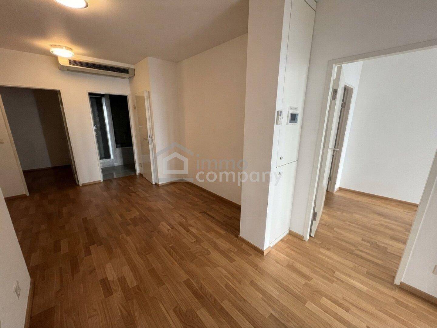 Geräumiger Flur mit Parkettboden und Klimaanlage, der einen Blick in angrenzende Zimmer ermöglicht.