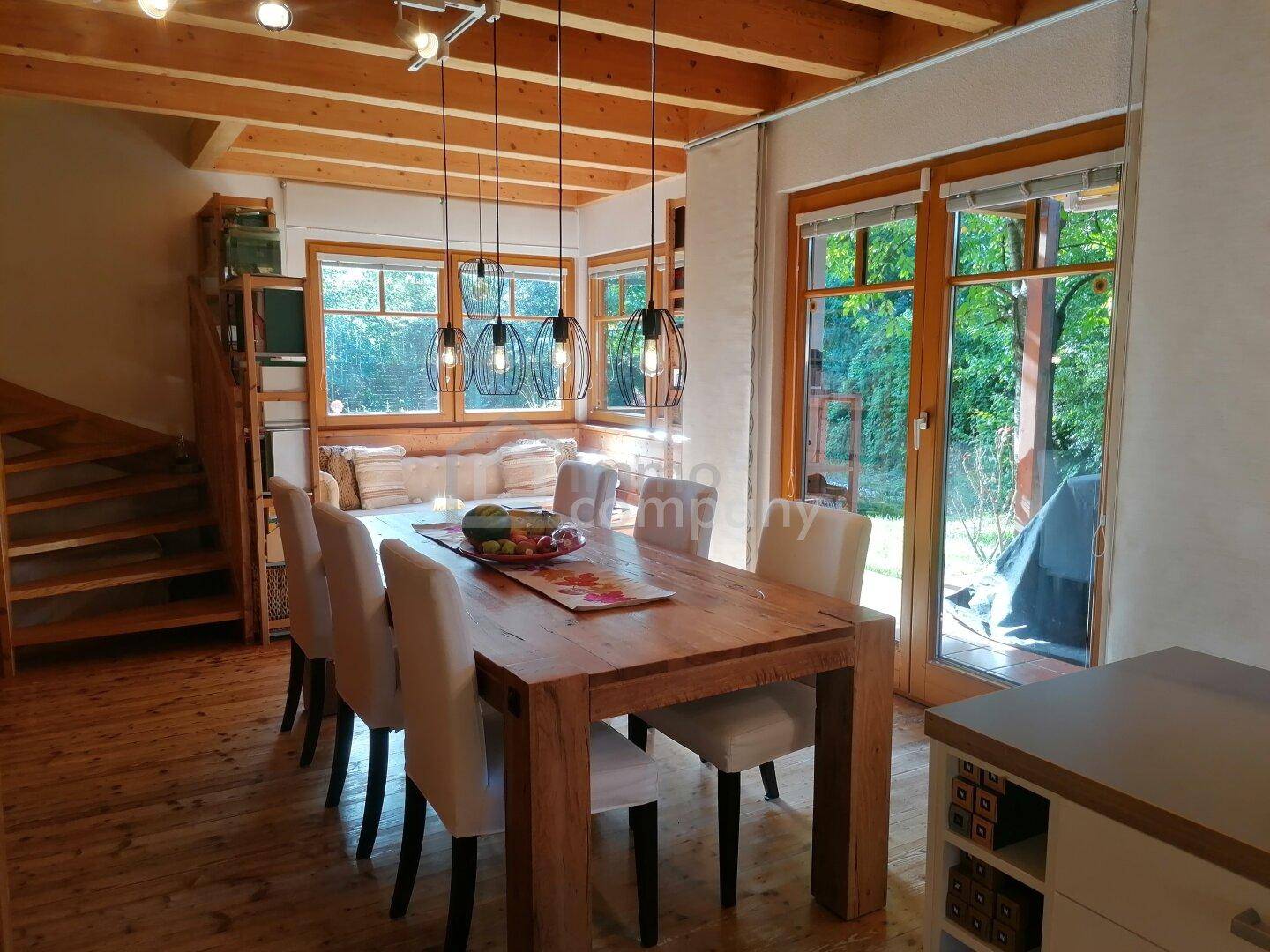 Heller Essbereich mit großem Holztisch, bequemen Stühlen und Blick in den Garten.