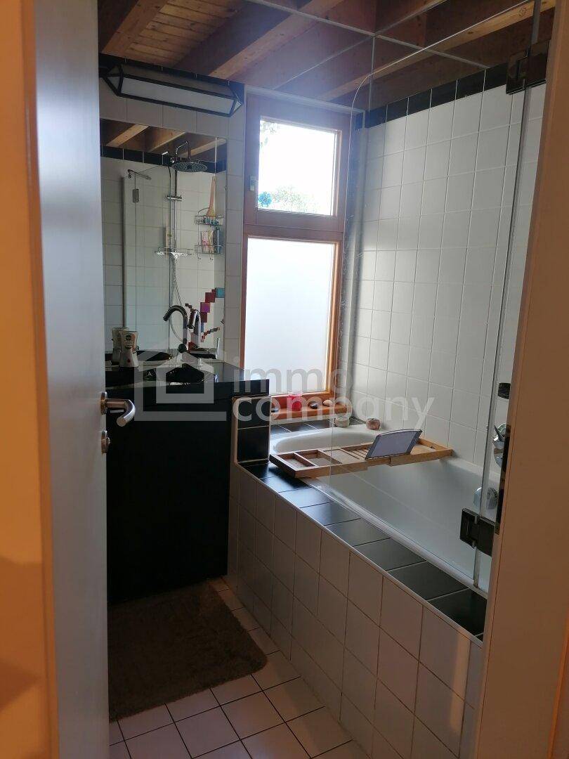 Modernes Badezimmer mit Badewanne, Dusche, Einzelwaschbecken und einem Fenster für Tageslicht.