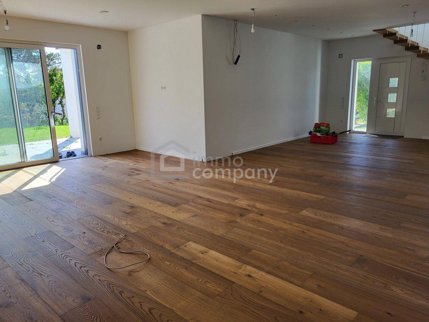 Heller Wohnbereich mit Holzboden, großen Schiebetüren und Zugang zu einer Terrasse oder Garten.