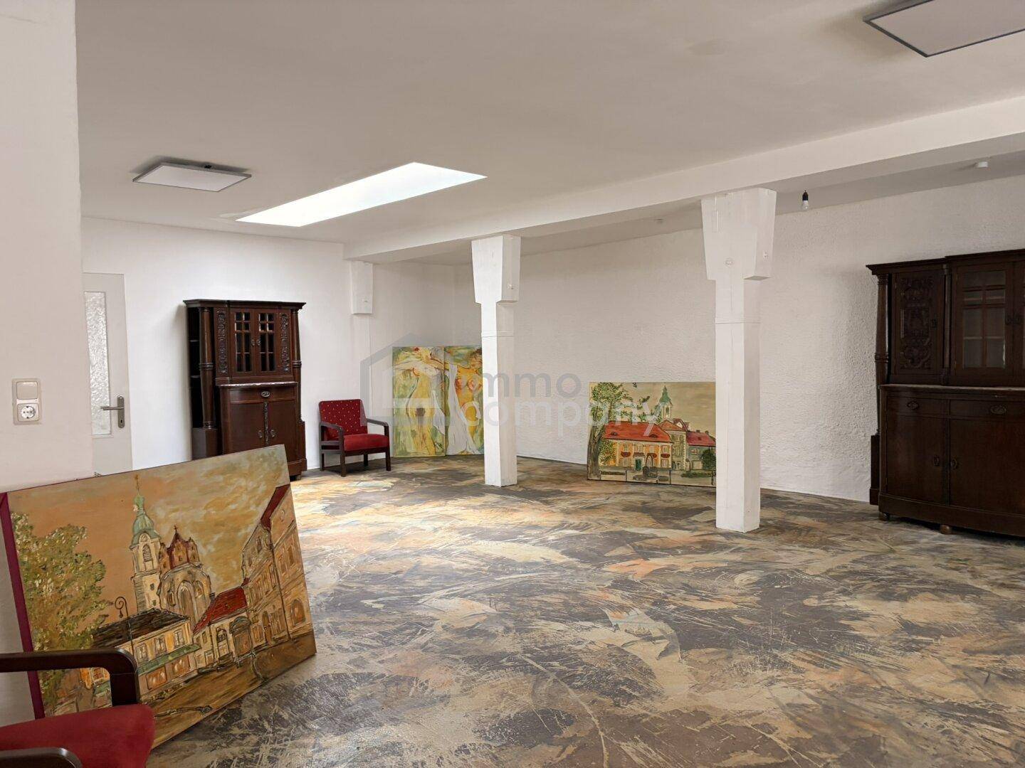 Großer, offener Raum mit Betonboden und weißen Wänden, der als Atelier oder Ausstellungsfläche dient.