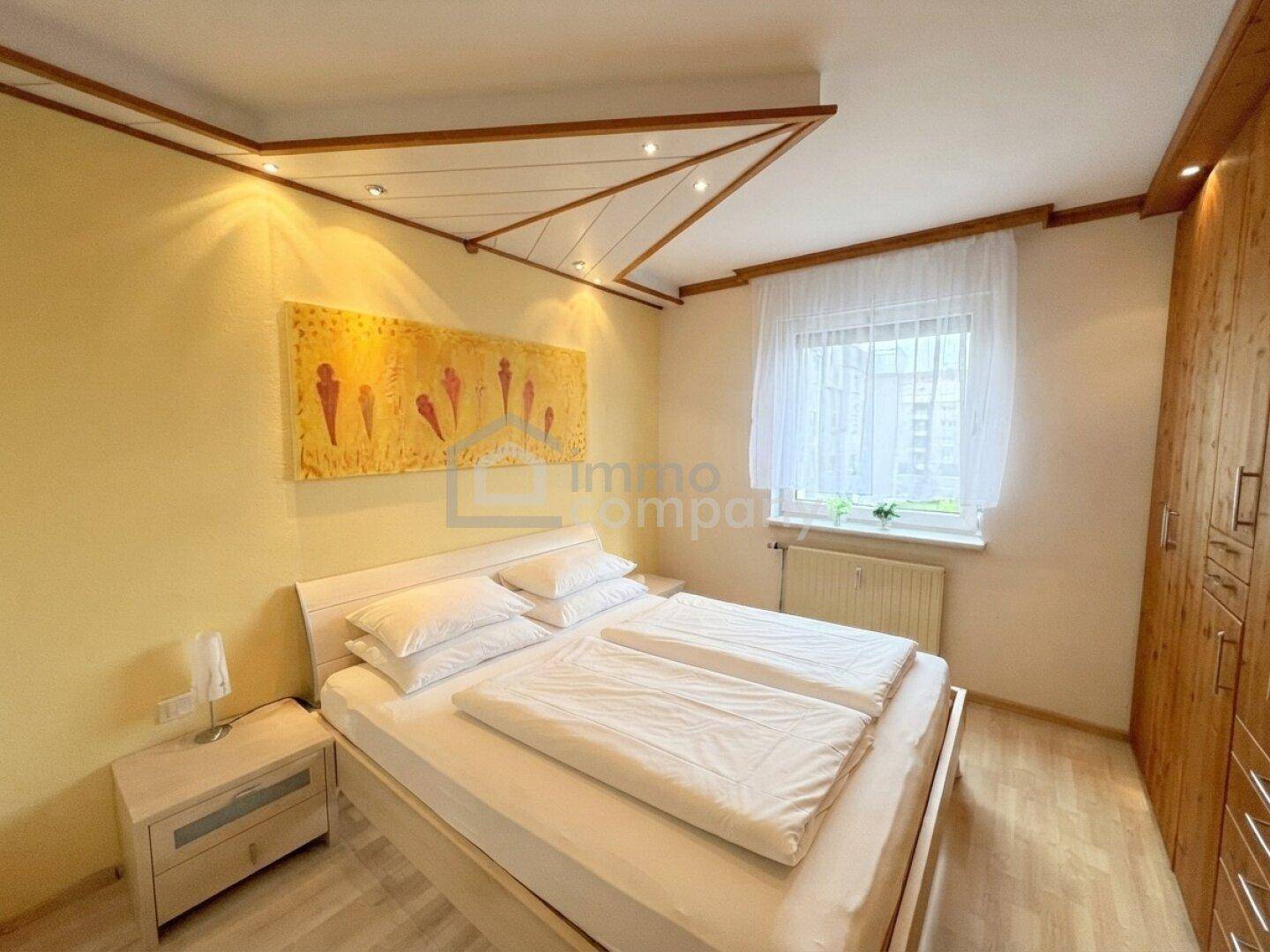 Gemütliches Schlafzimmer mit Doppelbett, Holzelementen und indirekter Deckenbeleuchtung für Atmosphäre.