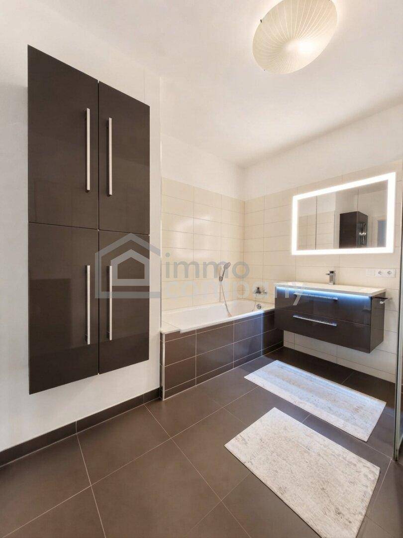 Modernes Badezimmer mit Badewanne, elegantem Waschtisch und praktischen Wandschränken.
