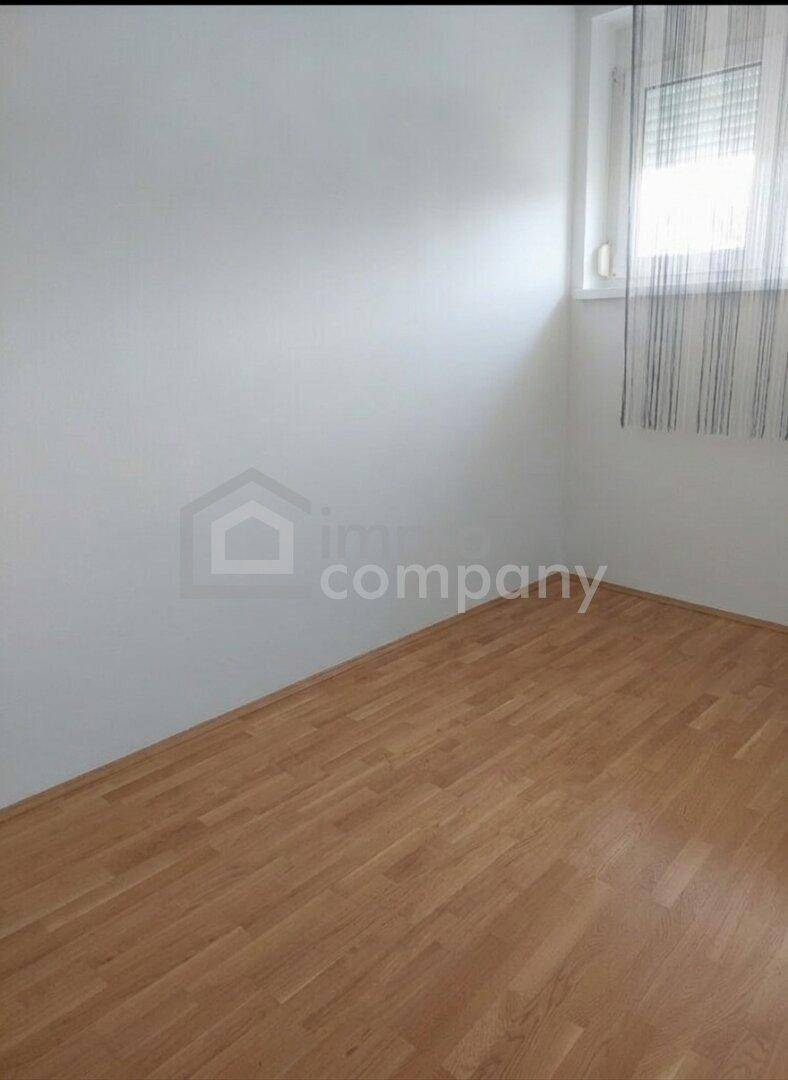 Heller Raum mit Holzboden, weißen Wänden und einem Fenster, bereit zur individuellen Gestaltung und Nutzung.