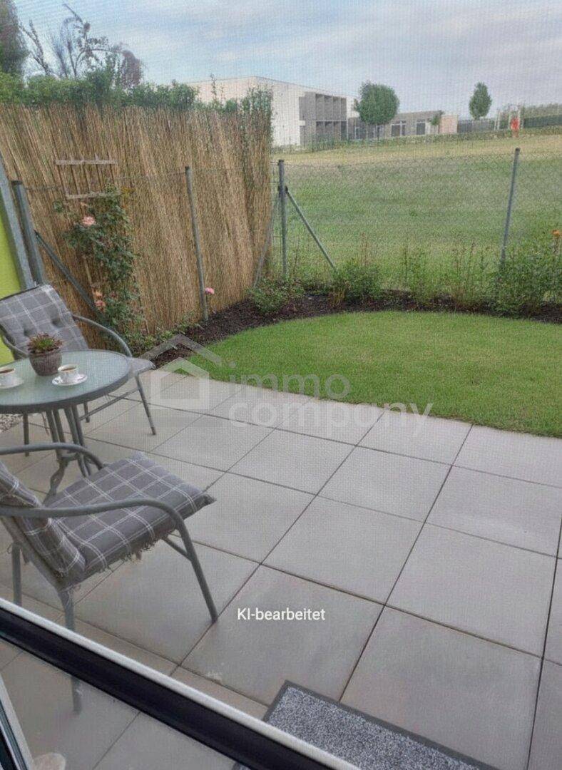 Gepflasterte Terrasse mit Gartenmöbeln, kleinem Rasen und Blick auf die umliegende Landschaft, ideal zum Entspannen.
