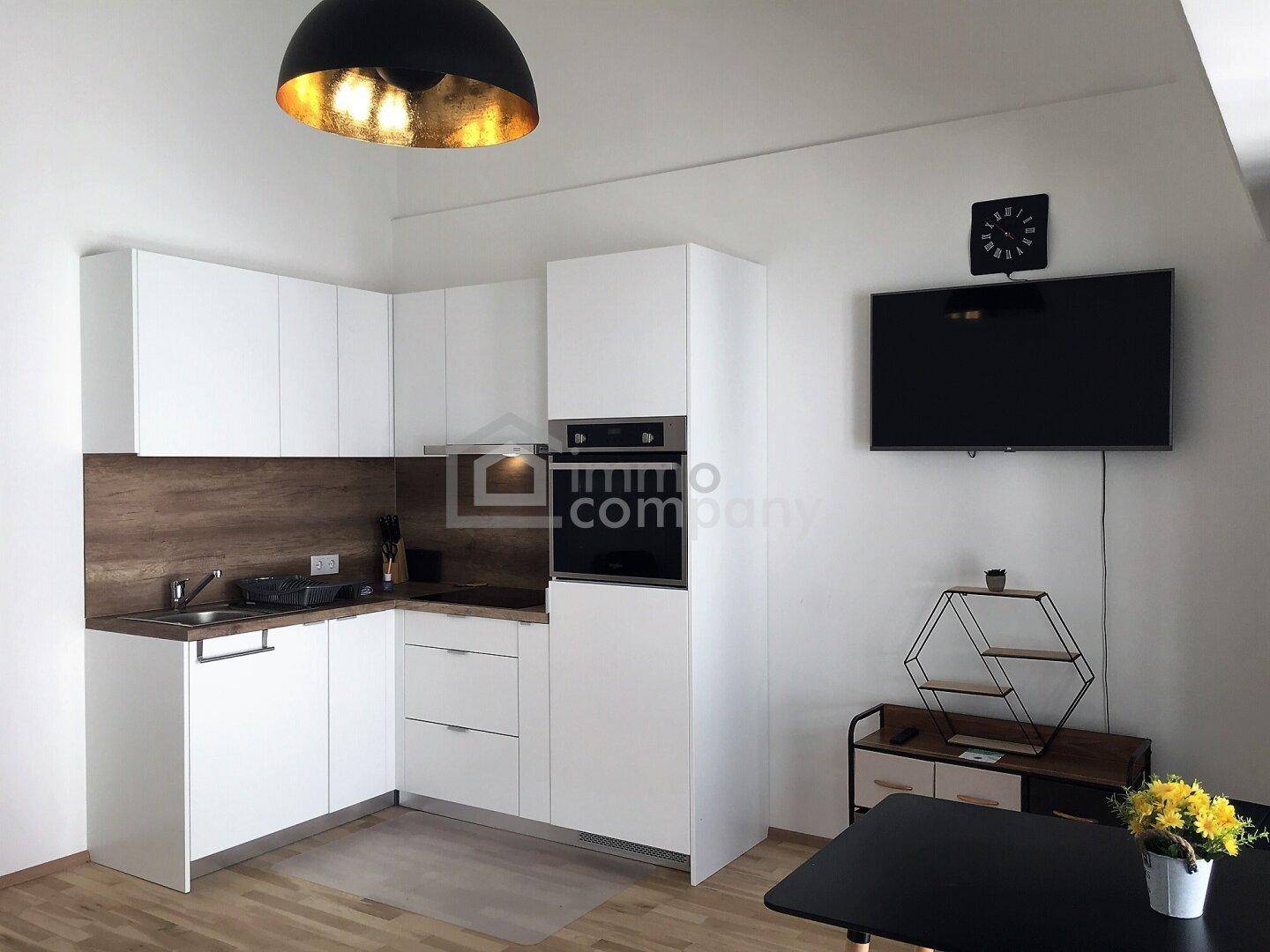 Moderne Küche mit weißen Schränken, Holzakzenten und integrierten Geräten in offenem Wohnbereich.