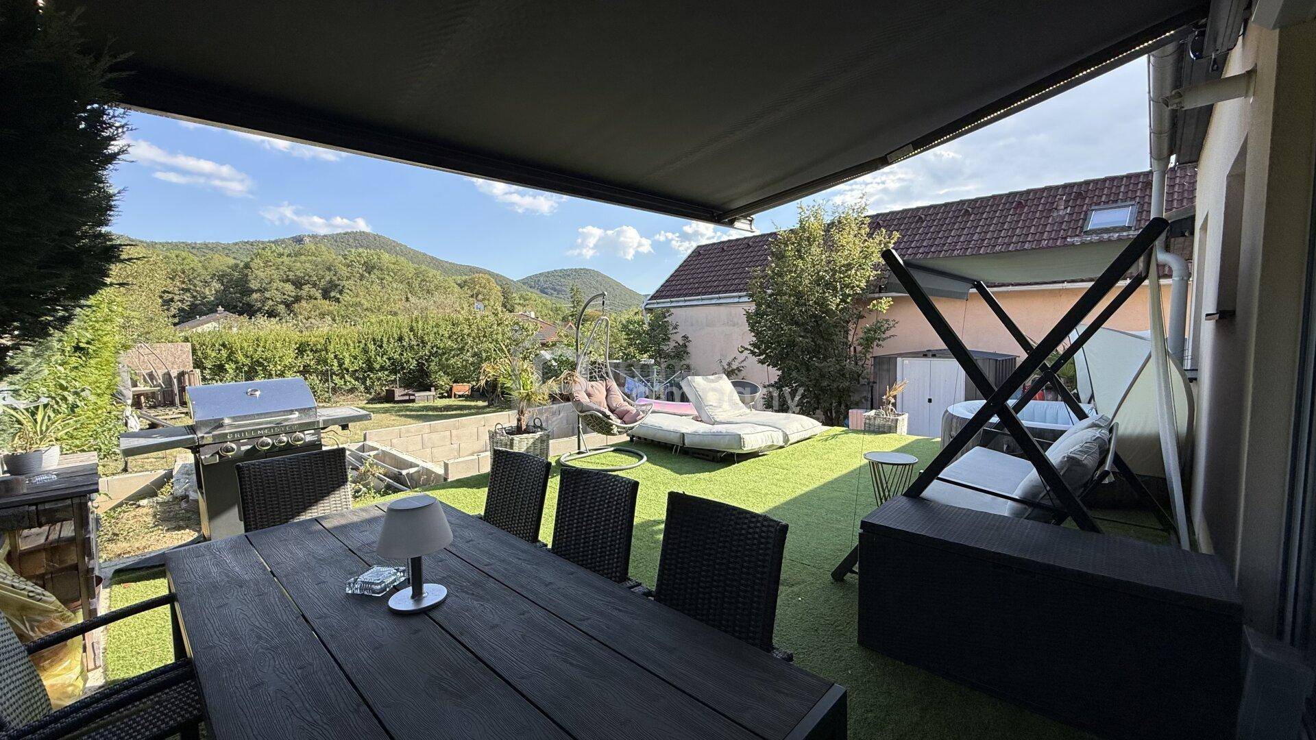 Überdachter Essbereich im Freien mit Grill, Liegestühlen und Blick auf die umliegende Landschaft.