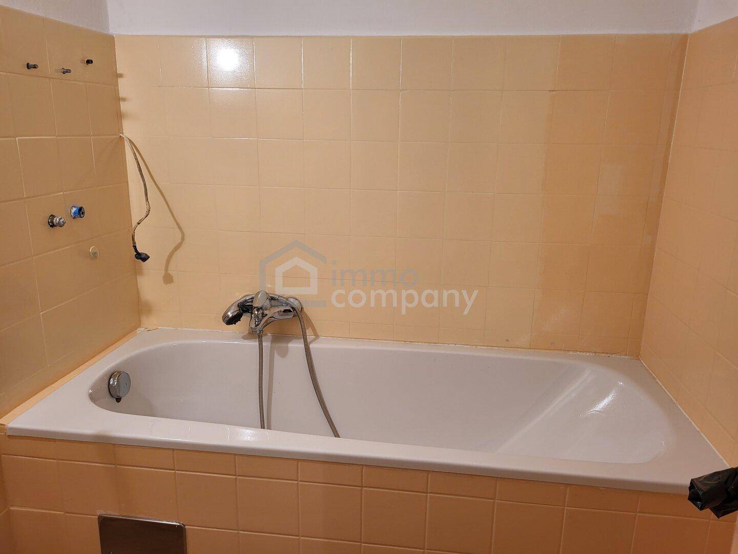 Badezimmer mit Badewanne und hellgelben Fliesen, im Stil der 80er Jahre.