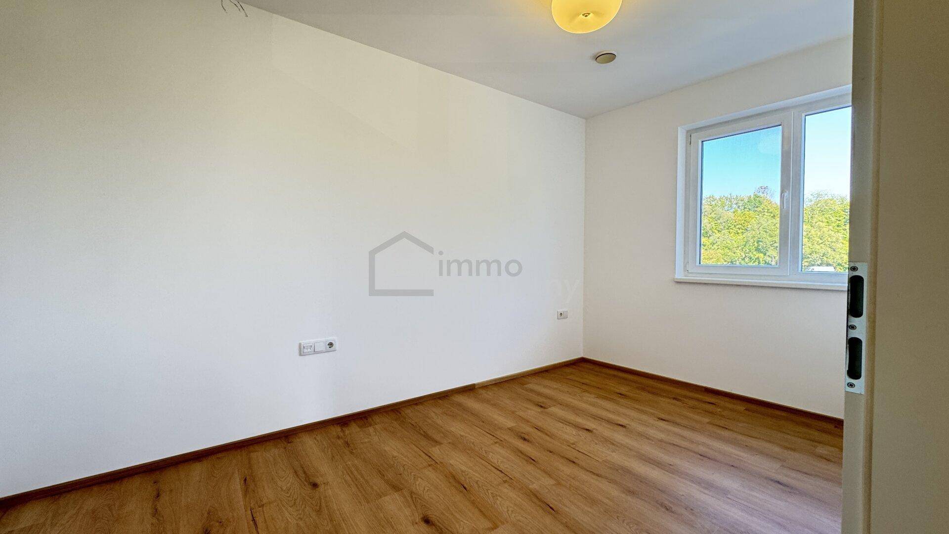 Helles, unmöbliertes Zimmer mit Laminatboden und Fenster, bietet viel Tageslicht.