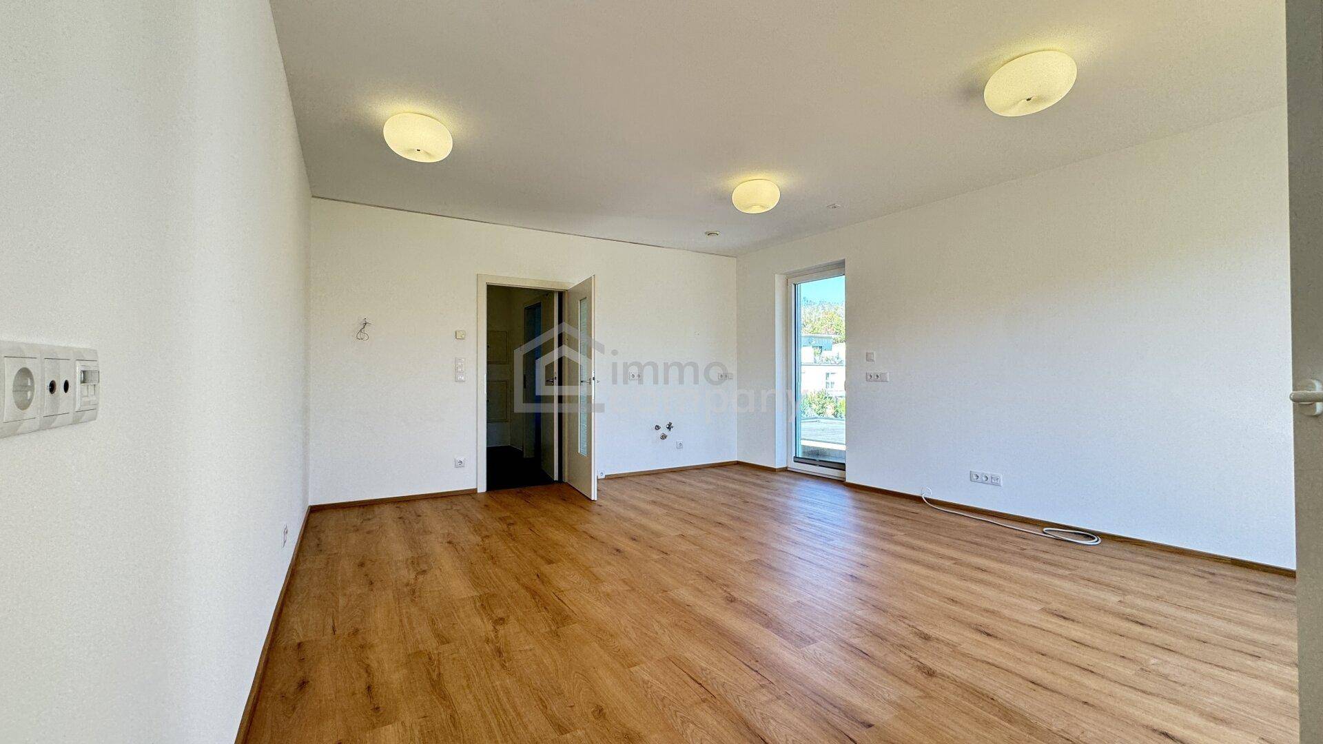 Helles, unmöbliertes Zimmer mit Laminatboden und weiß gestrichenen Wänden, bereit zum Einzug.