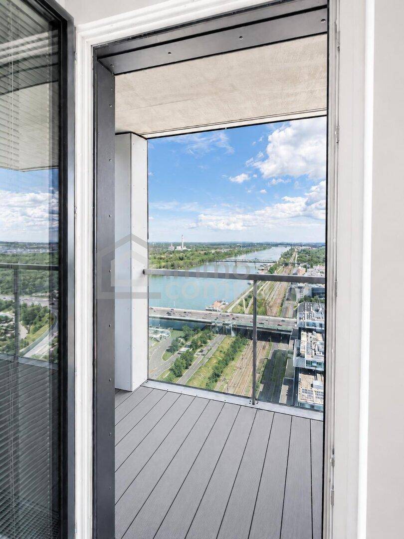 Kleiner Balkon mit Glasgeländer und weitem Blick auf den Fluss, Brücken und die Stadtlandschaft.