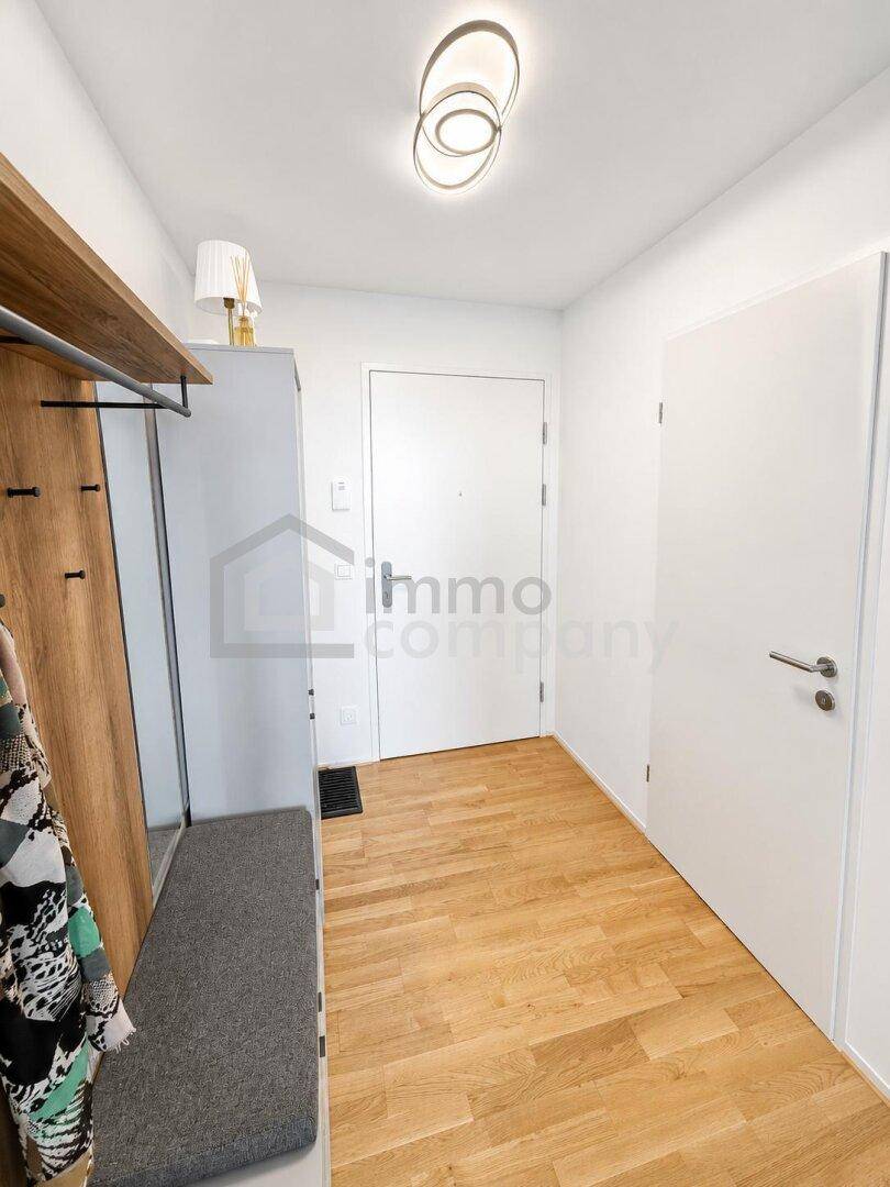 Heller Flur mit Garderobe, Sitzbank und modernem Holzdekor, einladend gestaltet.