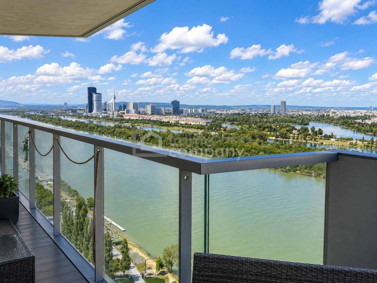 Geräumiger Balkon mit Glasgeländer und weitem Blick auf den Fluss und die grüne Umgebung.