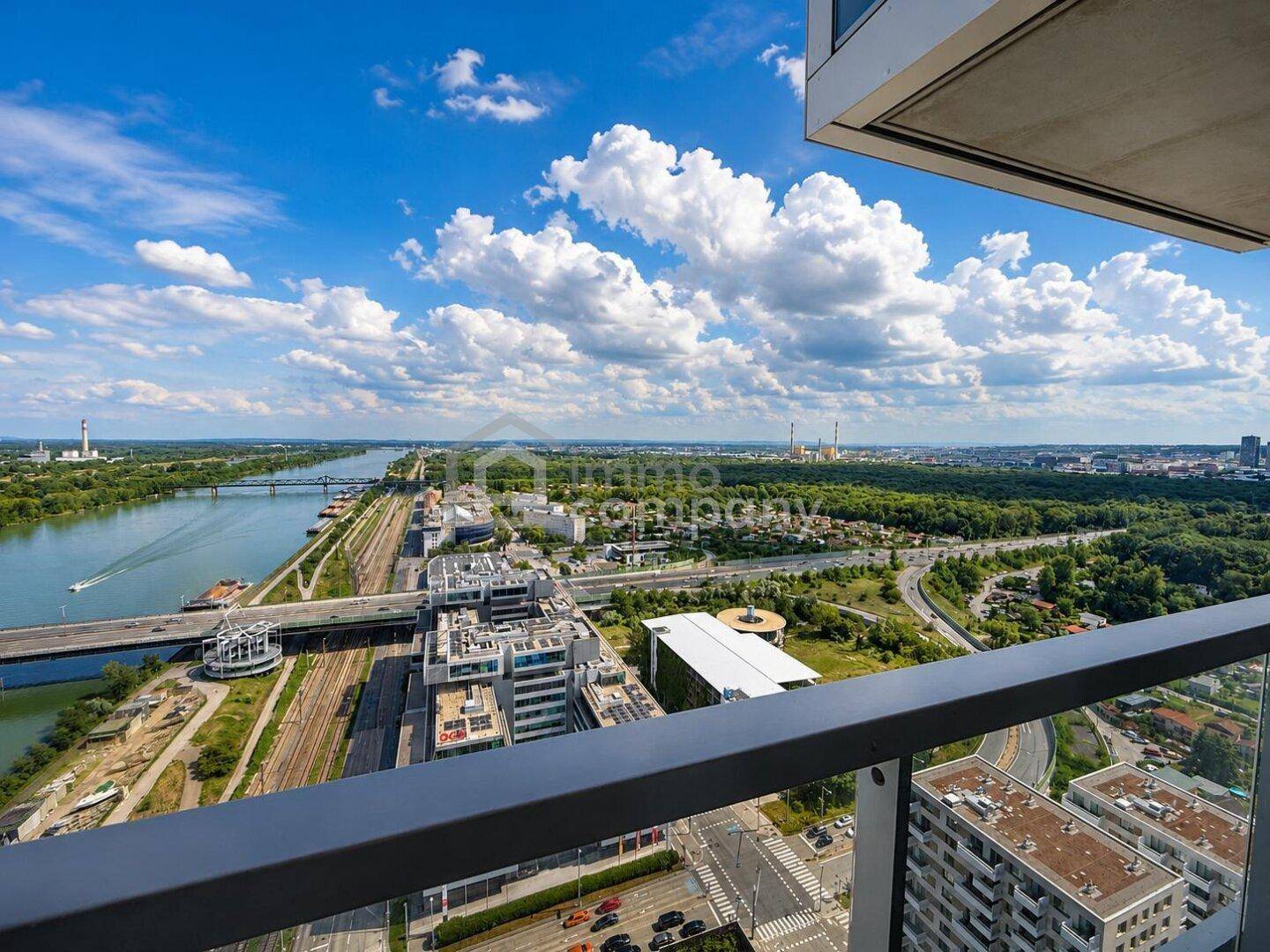 Panoramablick vom Balkon auf den Fluss, Brücken und die weitläufige Stadtlandschaft unter blauem Himmel.