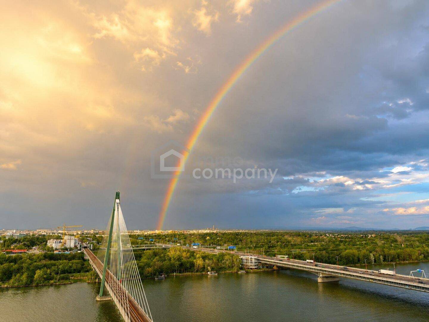 Malerischer Blick auf eine Brücke über dem Fluss mit einem beeindruckenden Regenbogen am Himmel.