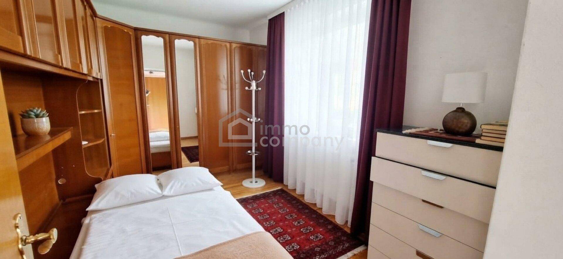 Gemütliches Schlafzimmer mit Holzeinbauschränken, Einzelbett und Teppichboden.