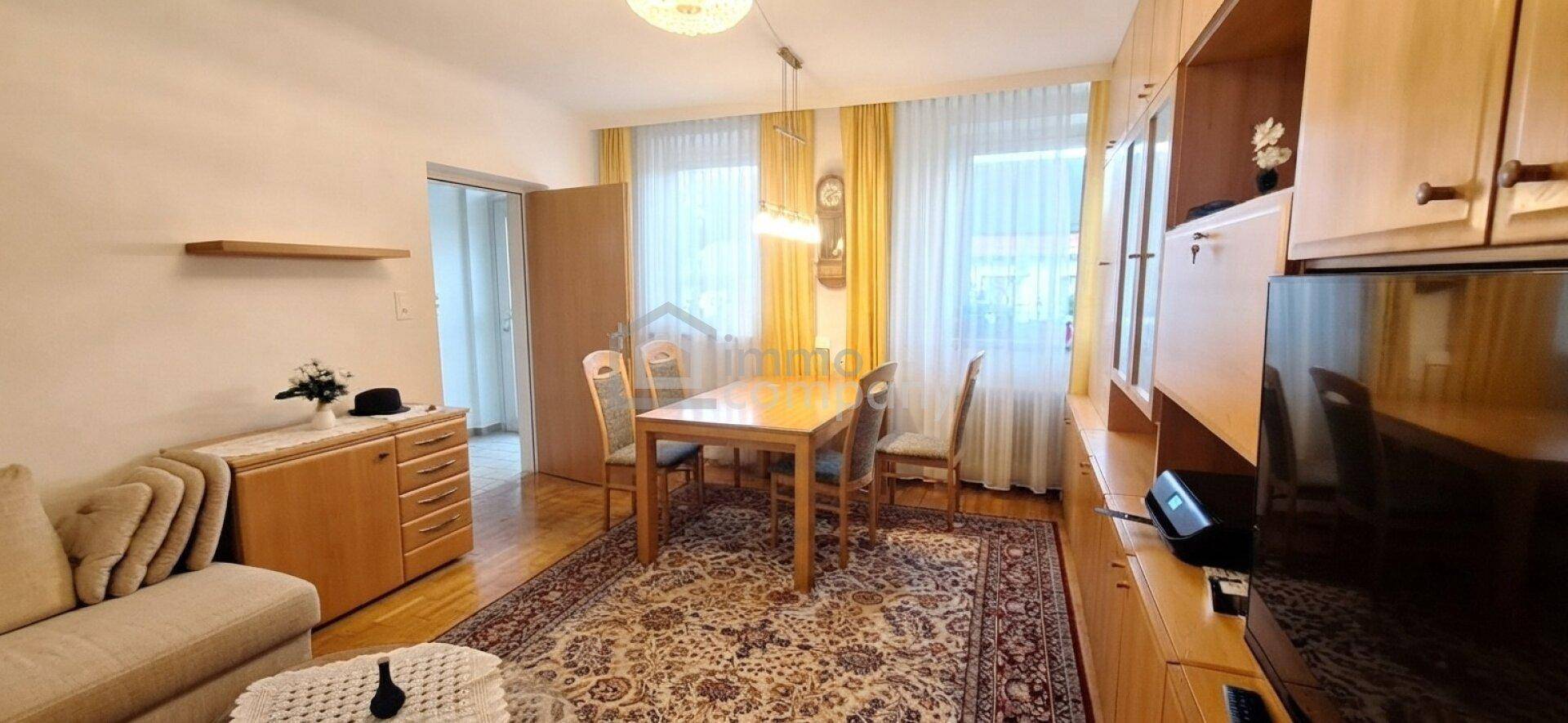 Gemütlicher Wohnbereich mit Esstisch, Teppichboden und großen Fenstern für viel Tageslicht.