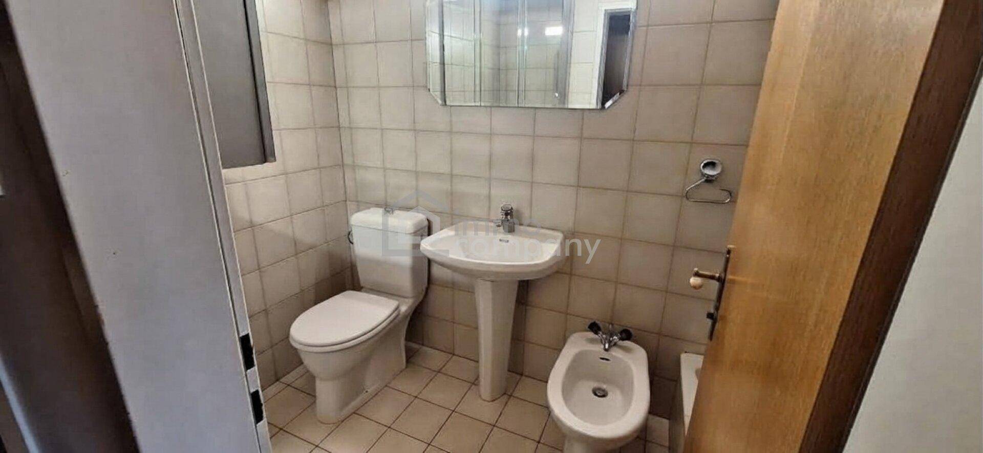 Kleines Badezimmer mit Toilette, Waschbecken und Bidet, komplett gefliest.